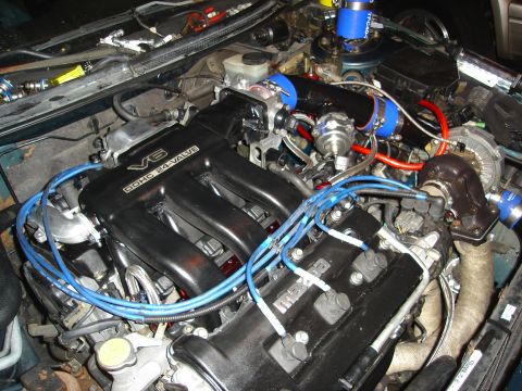 1995 Mazda MX-6 - Close-up view of a modified V6 engine, a turbocharger and custom plumbing.