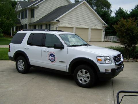2003 Ford Crown Victoria - A white Ford Explorer SUV is parked in front of a house with a three-car garage.