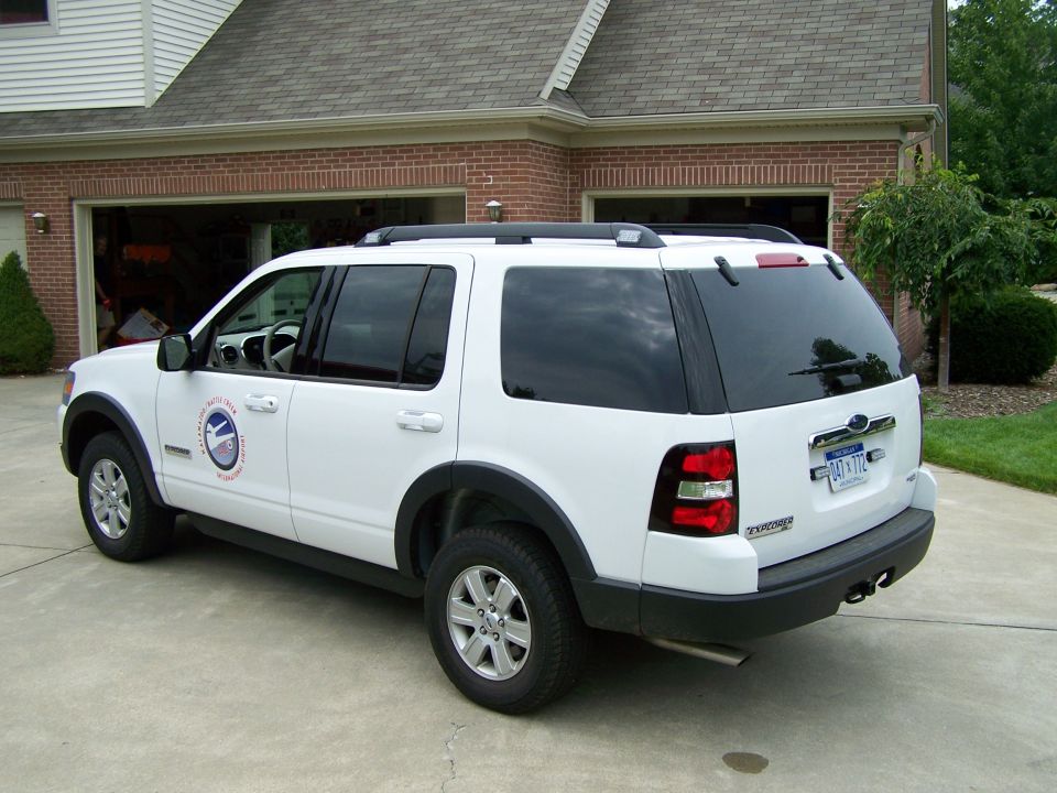 White Ford Explorer rear 3/4 view. Visible logo on door and license plate