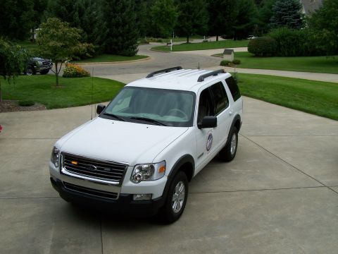 2003 Ford Crown Victoria - White Ford Explorer parked on a concrete driveway with a suburban home and trees in the background.