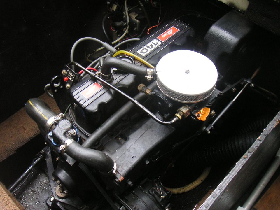 Black inboard marine engine with chrome air cleaner and '140' valve cover badge in a boat engine bay