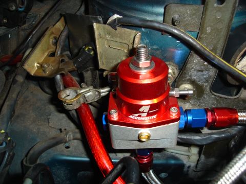 1995 Mazda MX-6 - Close-up view of an aftermarket Aeromotive fuel pressure regulator installed in an engine bay.