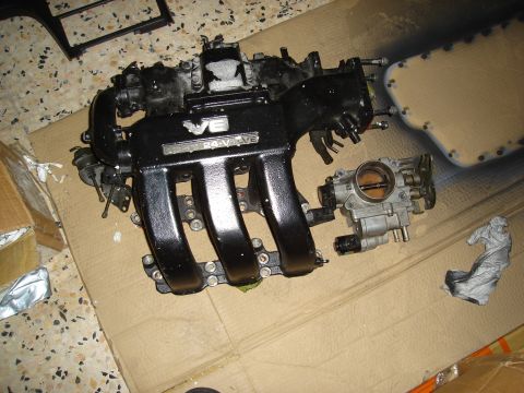 1995 Mazda MX-6 - Engine intake manifold and throttle body components laid out on a surface.