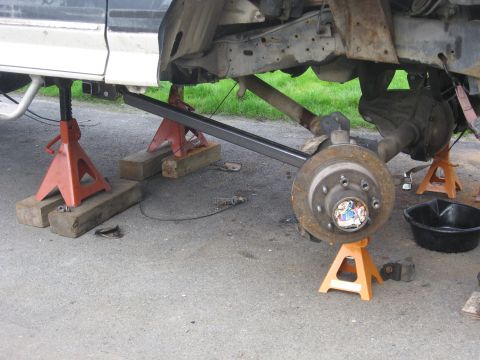 1990 Ford F-250 - The underbody of a 1990 Ford F-250 is visible, supported by jack stands as the suspension is worked on.