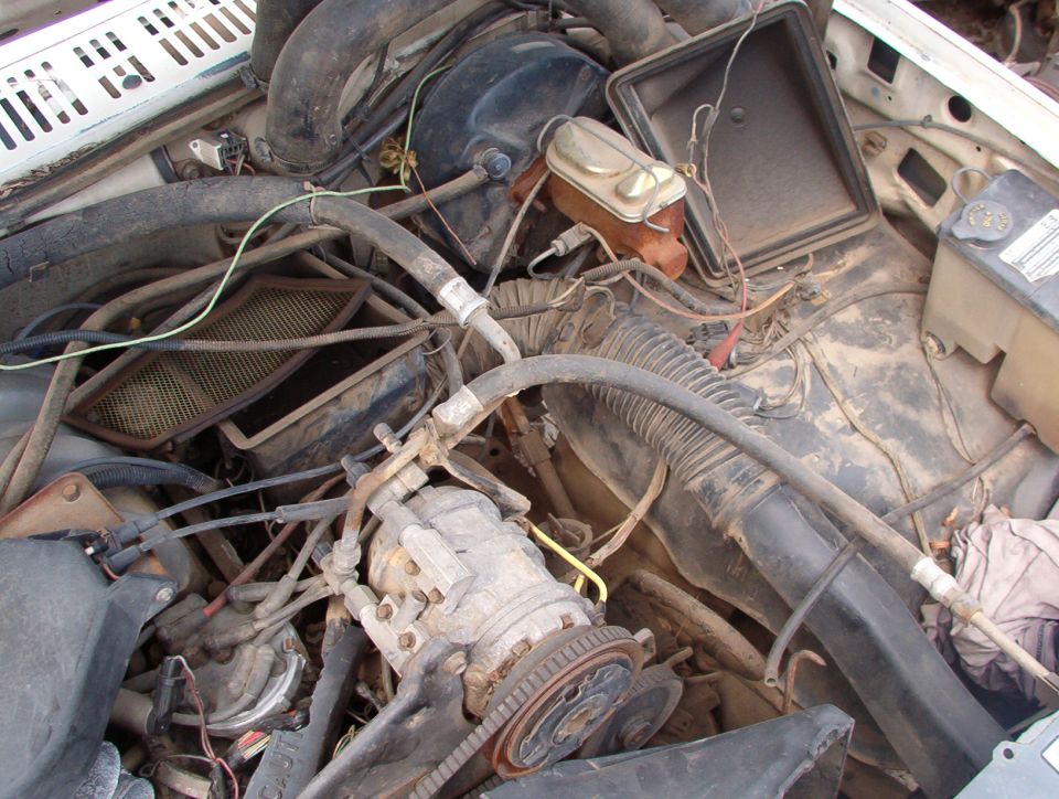 Dusty engine compartment showing A/C compressor and components