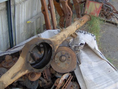 1978 Ford Bronco - Scrap metal pile includes a rusty axle housing and brake components.