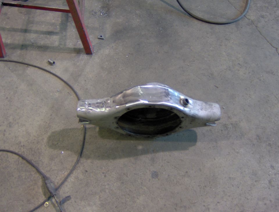 metal axle housing on concrete floor, red metal stand in background