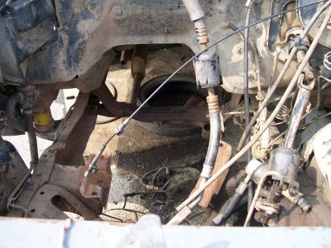 1989 Ford Bronco - Close-up view of a vehicle's engine bay and undercarriage, showing mechanical components and wear.