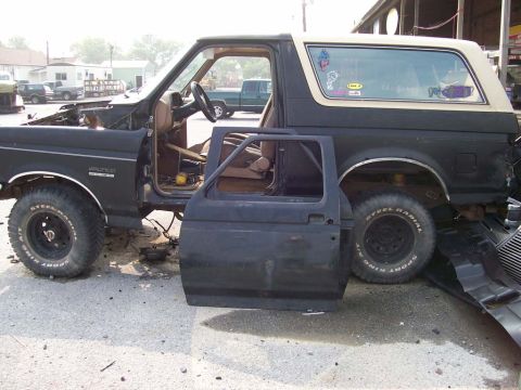 1989 Ford Bronco - This 1989 Ford Bronco is seen with its door removed and hood open, revealing its interior and engine bay.