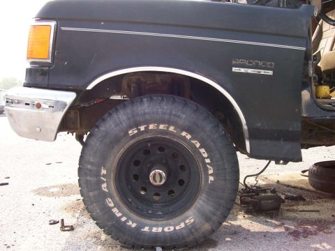 1989 Ford Bronco - Close-up of a Ford Bronco's front wheel and fender, showing the 'Bronco' emblem on the side.