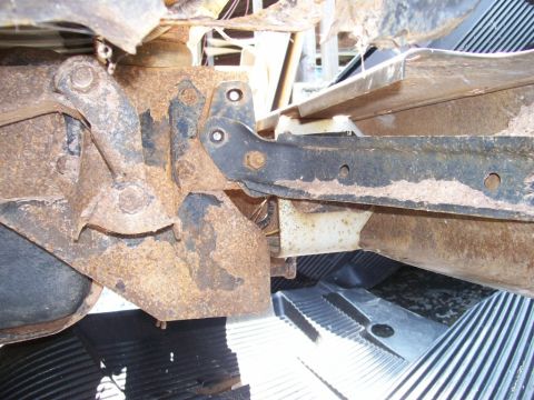 1989 Ford Bronco - The heavily corroded metal components of a vehicle's undercarriage are visible in this close-up shot.