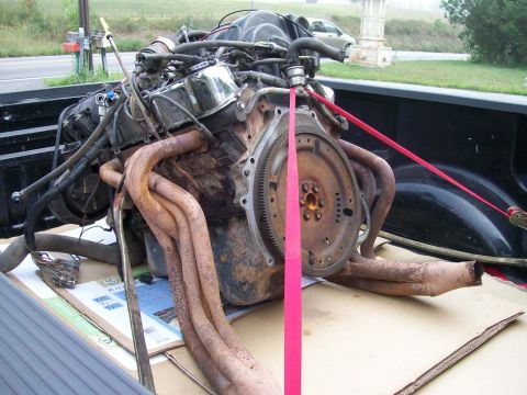 1989 Ford Bronco - A V8 engine, likely from a truck or SUV, is being transported in the bed of a pickup truck.