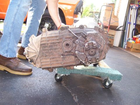1989 Ford Bronco - A transmission is being moved on a dolly in a garage setting.