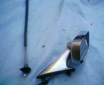 1973 Ford Ranchero - A chrome side mirror and a black antenna are displayed on a blue surface.