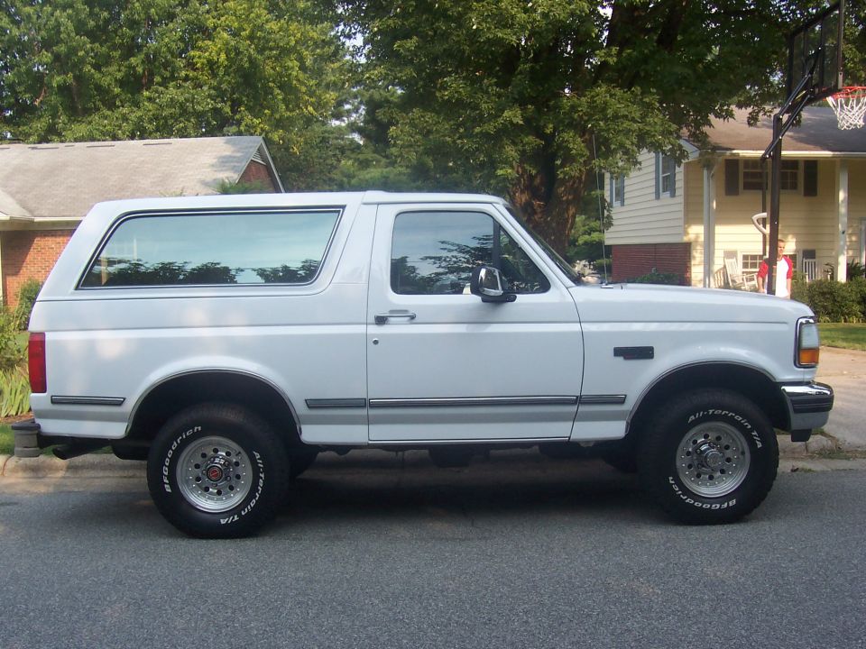 White full-size Ford Bronco side profile on a suburban street with BFGoodrich All-Terrain tires