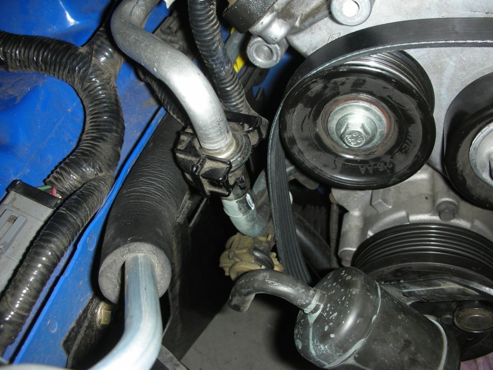 Close-up of engine belt and pulleys with hoses and wiring