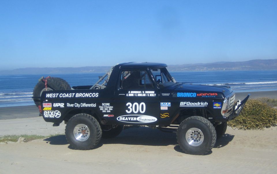 Black off-road race Bronco number 300 parked on a beach by the ocean
