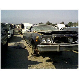 1973 Ford Ranchero - A black pickup truck sits in a junkyard, showing signs of damage and disrepair.