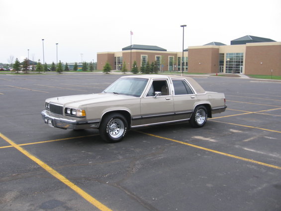 Tan full-size sedan front three-quarter view in a large parking lot