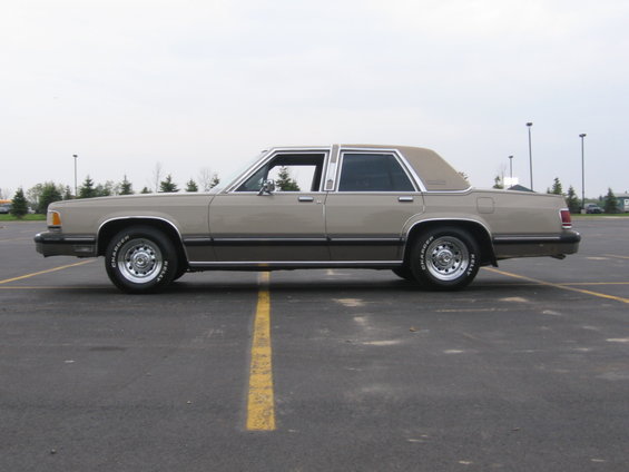 Tan full-size sedan driver-side profile under an overcast sky