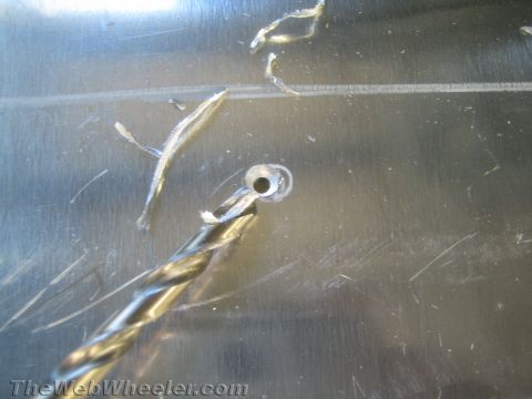 1987 Suzuki Samurai - Drilling a hole in a metal surface, with metal shavings visible around the freshly drilled hole.