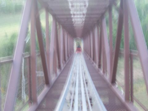 1972 Ford Ranchero - A red vehicle travels down a metal track within a tunnel-like structure.