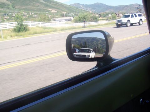 1972 Ford Ranchero - A white classic car is seen in the side mirror while driving on a highway with a white SUV ahead.