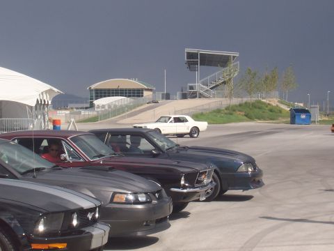 1972 Ford Ranchero - Cars parked at a track with a grandstand and buildings in the background under a dark sky.