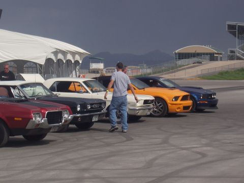 1972 Ford Ranchero - Several cars are parked in a row on asphalt with tire marks visible.