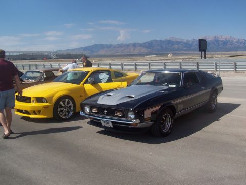 1972 Ford Ranchero - A black 1971 Ford Mustang Mach 1 is parked next to a yellow modern Ford Mustang on a sunny day.