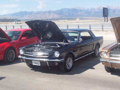 1972 Ford Ranchero - A black 1965 Ford Mustang coupe is displayed with its hood open, parked next to other vehicles.