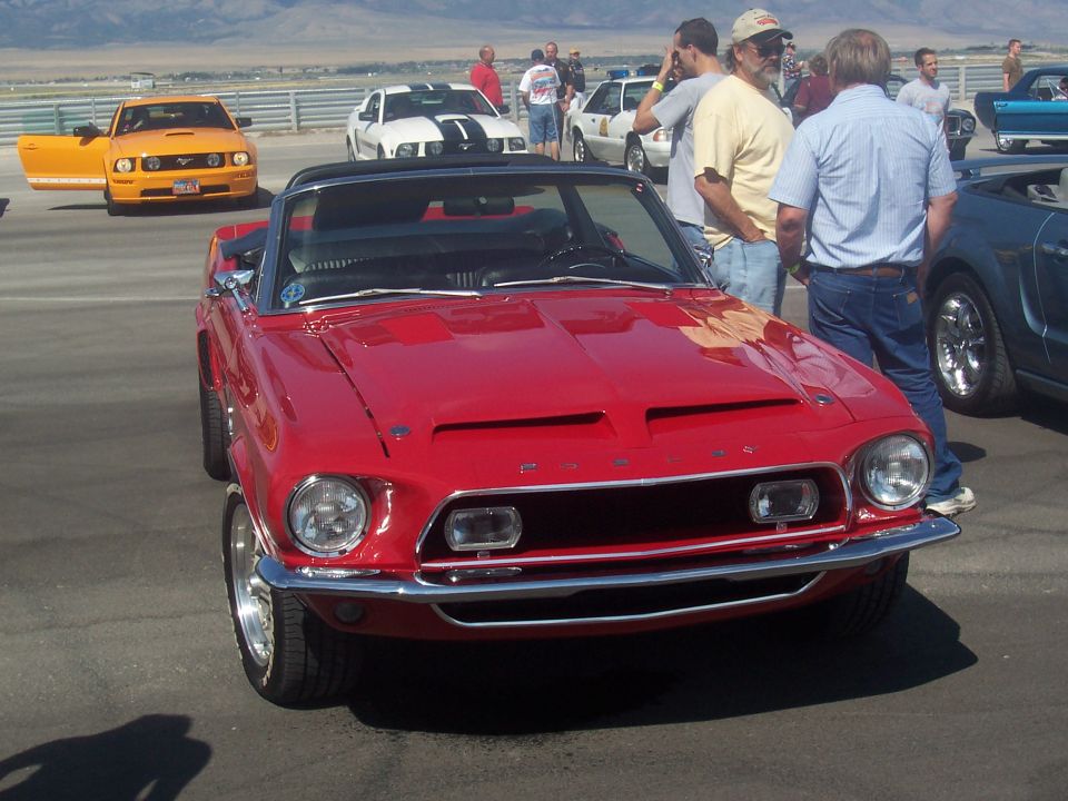 Red 1967 Ford Mustang convertible with hood scoops and chrome bumper, viewed from the front