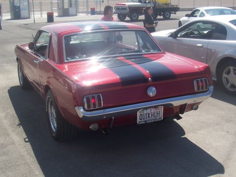 1972 Ford Ranchero - A classic red coupe with black racing stripes is parked in a lot, with other vehicles nearby.