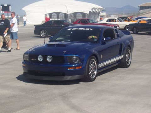 1972 Ford Ranchero - A blue Ford Mustang Shelby GT350 is parked at an outdoor event with other vehicles visible in the background.