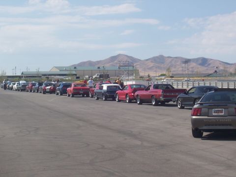 1972 Ford Ranchero - A diverse collection of vehicles, including classic muscle cars and modern sedans, are lined up on a track under a clear sky.