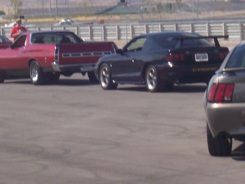 1972 Ford Ranchero - A red 1972 Ford Ranchero is parked next to a black coupe on a racetrack.