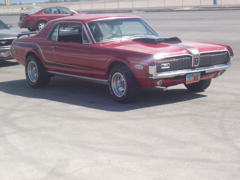 1972 Ford Ranchero - A red 1969 Mercury Cougar XR7 is parked in an outdoor lot with another vehicle visible in the background.