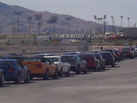 1972 Ford Ranchero - Multiple vehicles are parked in a line on an asphalt lot with mountains in the background.