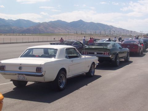 1972 Ford Ranchero - A white 1965 Ford Mustang coupe is parked in a line of vehicles with mountains in the background.