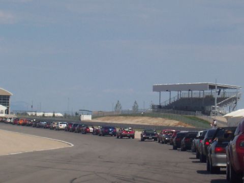 1972 Ford Ranchero - Multiple vehicles are parked in a line on a paved track, with grandstands visible in the distance.
