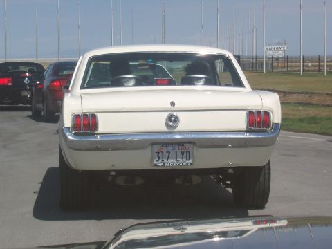 1972 Ford Ranchero - A white 1965 Ford Mustang is seen from the rear, parked in a line of vehicles.