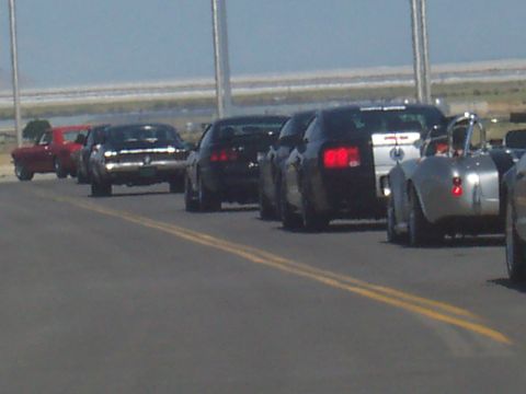 1972 Ford Ranchero - A procession of vehicles, including a classic red pickup and a silver convertible, travels down a road.