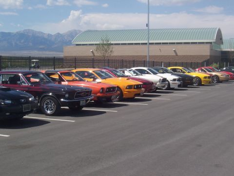 1972 Ford Ranchero - A row of Ford Mustangs, with the earliest visible appearing to be from 1972, are parked in a lot with mountains in the background.