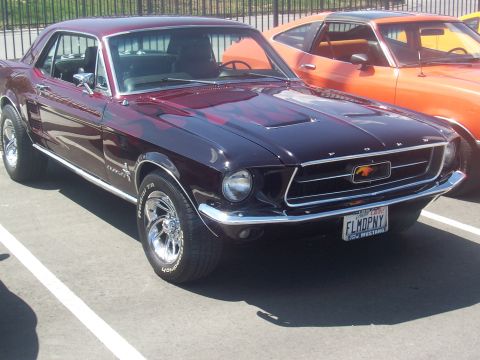 1972 Ford Ranchero - Front view of a dark red 1967 Ford Mustang coupe with custom flame paint and chrome wheels.