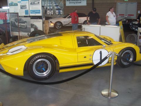 1972 Ford Ranchero - A yellow Ford GT40 race car is displayed indoors with stanchions in front of it.