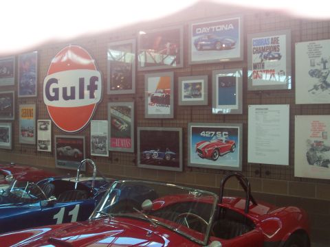 1972 Ford Ranchero - A collection of vintage racing posters and memorabilia adorns a wall above two classic sports cars.
