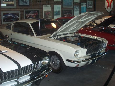 1972 Ford Ranchero - A white 1965 Ford Mustang coupe is displayed with its hood open, alongside other classic cars.