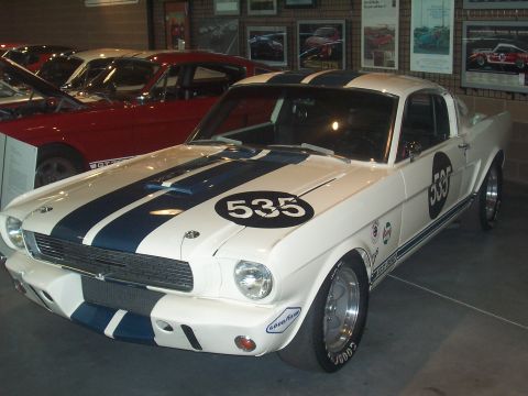 1972 Ford Ranchero - A white 1965 Ford Mustang Shelby GT350 race car is displayed indoors with another red Mustang behind it.