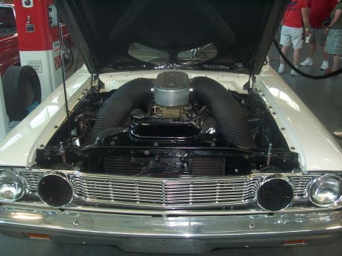 1972 Ford Ranchero - The engine bay of a white 1962 Ford Falcon is open, revealing a V8 engine with dual air intake snorkels.