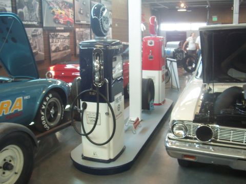 1972 Ford Ranchero - Vintage gas pumps and cars displayed indoors, possibly at a museum or show.